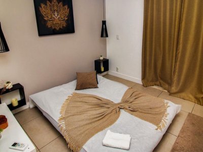 Ambiente de massagem em tonalidades bege e branco no Aruna SPA em Campinas, com cama, lençóis, travesseiro e panos higienizados e limpos, oferecendo um espaço elegante e confortável para clientes e massagistas.