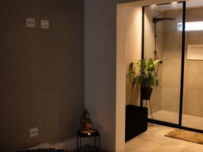 Banheiro da Casa de Massagem Aruna SPA em Campinas com tonalidades preto e bege, incluindo uma ducha moderna, projetado para oferecer uma experiência relaxante e sofisticada.